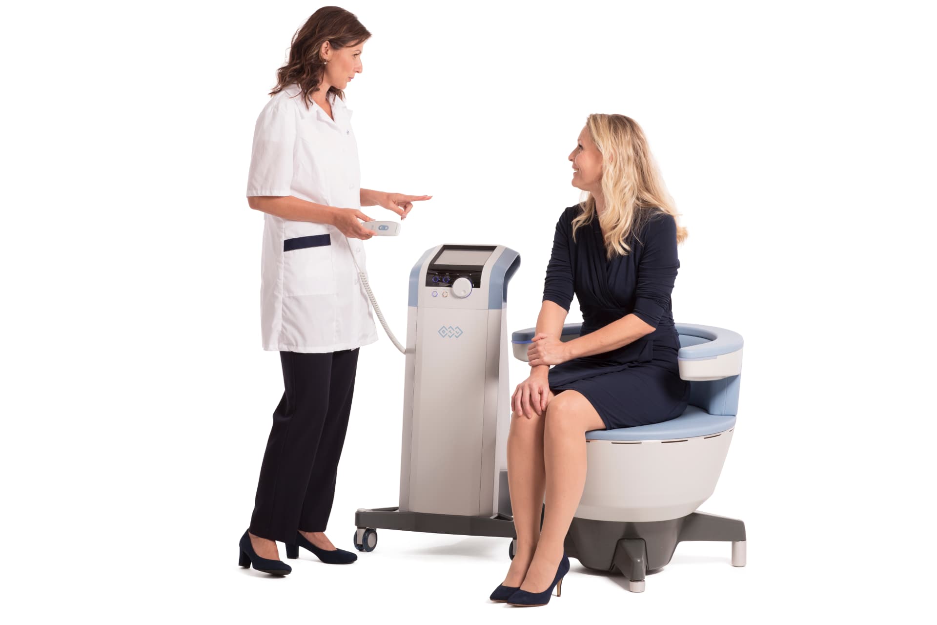 A clinician in a white coat holds the Emsella handheld controller beside the treatment chair while a patient sits fully clothed